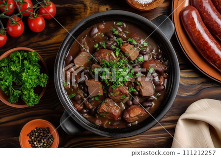 Top view of traditional Brazilian dish feijoada in black clay bowl on a wooden table Top view of traditional Brazilian dish feijoada in black clay bowl on a wooden table 111212257