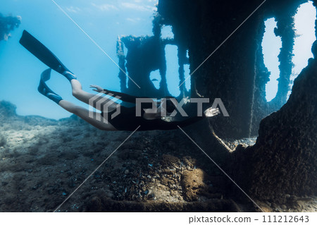 Sporty woman freediver swims underwater among the ruins of a ship. Freediving at wreck ship Sporty woman freediver swims underwater among the ruins of a ship. Freediving at wreck ship 111212643