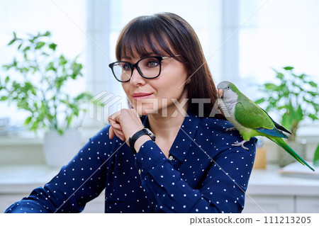Close-up of green parrot on the shoulder of a female owner Close-up of green parrot on the shoulder of a female owner 111213205