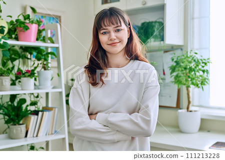 Portrait of smiling female teenager looking at camera with crossed arms in home 111213228