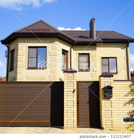 Decorative metal on the roof of a brick house. Fence made of cor 111213407