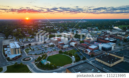 Muncie, IN sunset with golden sun over horizon aerial of downtown buildings and park Muncie, IN sunset with golden sun over horizon aerial of downtown buildings and park 111213995