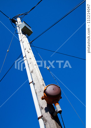 Low Angle View of Weathered Utility Pole Against Blue Sky in Urban Setting Low Angle View of Weathered Utility Pole Against Blue Sky in Urban Setting 111214047