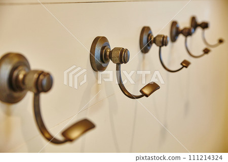 Minimalist Bronze Coat Hooks on Cream Wall, Eye-Level View 111214324