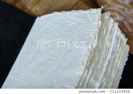 Textured Paper Stack with Deckle Edges and Rustic Backdrop 111214456