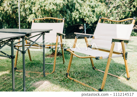 Enjoy a picnic in the great outdoors with an outdoor camping tent shelter, tables, and chairs. This suburban relaxation setup in the summer provides a comfortable and shaded spot for your picnic. Enjoy a picnic in the great outdoors with an outdoor camping tent shelter, tables, and chairs. This suburban relaxation setup in the summer provides a comfortable and shaded spot for your picnic. 111214517