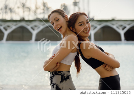 Two smiling young female sportswomen have a rest after morning jogging outdoors Two smiling young female sportswomen have a rest after morning jogging outdoors 111215035