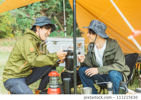 Male camper pitching a tent and camping at a campsite in autumn and winter Male camper pitching a tent and camping at a campsite in autumn and winter 111215630