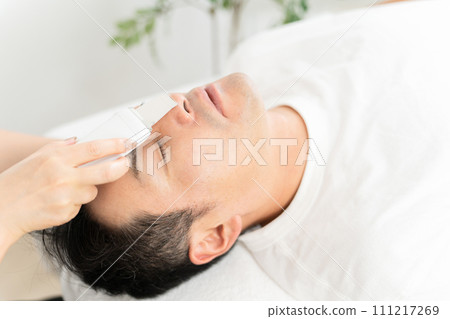 Water peeling to remove dirt from pores at men's facial beauty salon 111217269