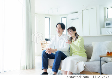 Young couple watching TV in the living room Young couple watching TV in the living room 111217573