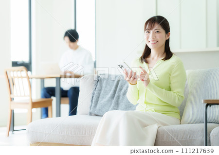 A middle-aged couple watching a smartphone in the living room A middle-aged couple watching a smartphone in the living room 111217639