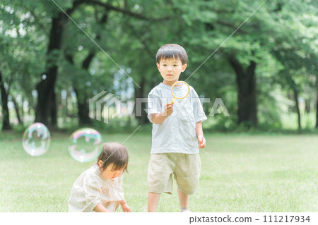 Siblings and children playing with soap bubbles in the forest/park (picnic/camping/outdoors) Siblings and children playing with soap bubbles in the forest/park (picnic/camping/outdoors) 111217934