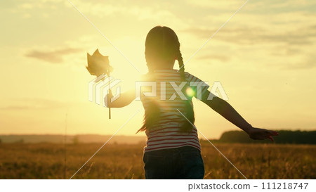 Cute little girl running windmill pinwheel rotate toy at summer field sunset sunrise sky slowmo 111218747