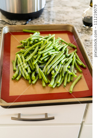 Watch as fresh green beans are beautifully roasted to perfection on a baking sheet with a silicone mat, adding a burst of flavor to your meal. 111219079