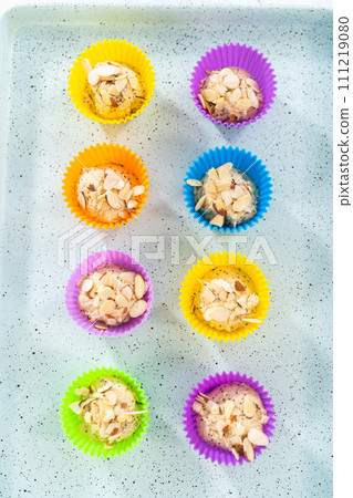 Scooping cupcake batter with dough scoop into silicon muffin liners to lemon poppy seed muffins. 111219080