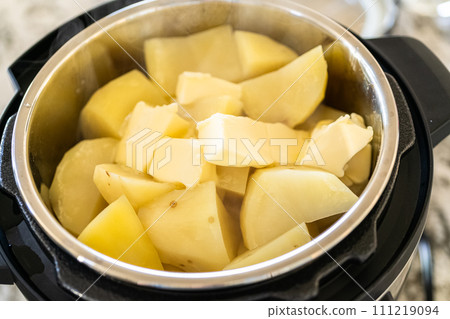 In a sleek modern kitchen, preparing velvety mashed potatoes using a pressure cooker for a quick and delicious meal. 111219094