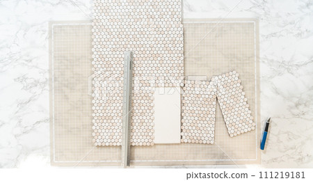 In the process of mounting peel and stick mosaic tiles onto a foam board, perfect for enhancing a food photography studio's aesthetic. 111219181
