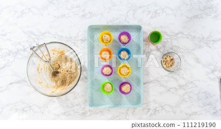 Flat lay. Scooping cupcake batter with dough scoop into silicon muffin liners to lemon poppy seed muffins. 111219190