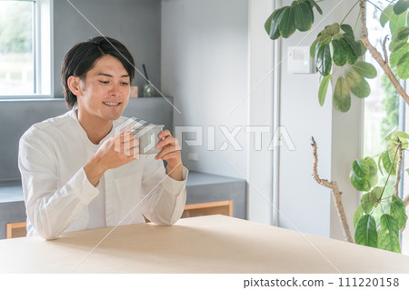 Young Asian man drinking coffee, hot water, black tea, relaxing at home 111220158