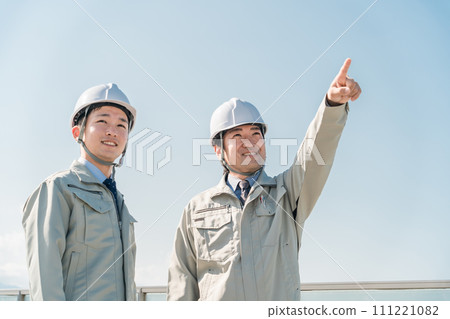 Workers wearing work clothes standing in the blue sky (construction, architecture, design, real estate, civil engineering, construction, site supervision, transportation) 111221082