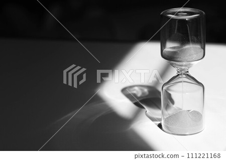 Hourglass on the desk, impressive light, shadow, and glass reflection 111221168