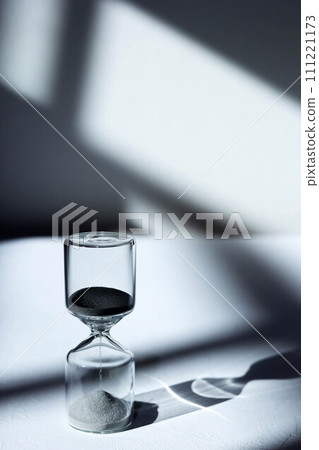 Hourglass on the desk, impressive light, shadow, and glass reflection 111221173