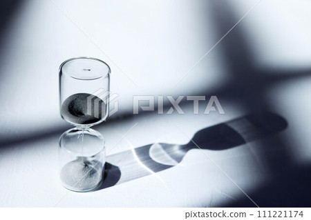 Hourglass on the desk, impressive light, shadow, and glass reflection Hourglass on the desk, impressive light, shadow, and glass reflection 111221174