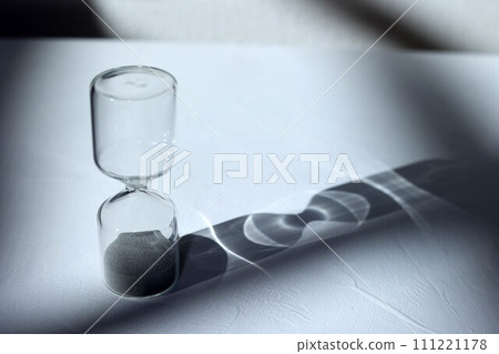 Hourglass on the desk, impressive light, shadow, and glass reflection 111221178