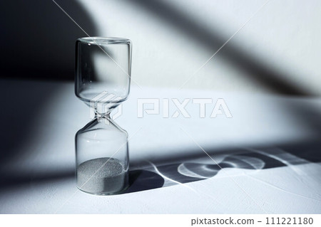 Hourglass on the desk, impressive light, shadow, and glass reflection Hourglass on the desk, impressive light, shadow, and glass reflection 111221180