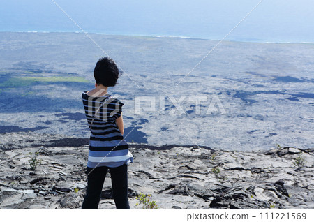 A woman looking down at the sea from a rocky place A woman looking down at the sea from a rocky place 111221569