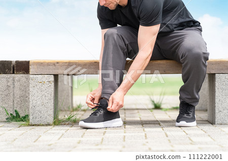 Caucasian man in sportswear tying shoelaces on sneakers to prepare for exercise 111222001