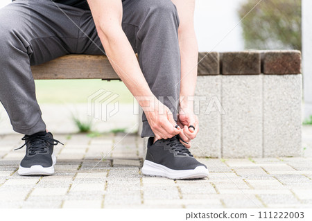 穿運動服的白人男子在運動鞋上系鞋帶，準備鍛煉 111222003