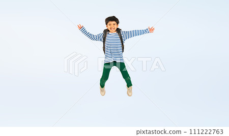Elementary school boy jumping with a smile while carrying a school bag on his back Elementary school boy jumping with a smile while carrying a school bag on his back 111222763