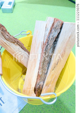 Firewood for a bonfire in a yellow bucket 111223076