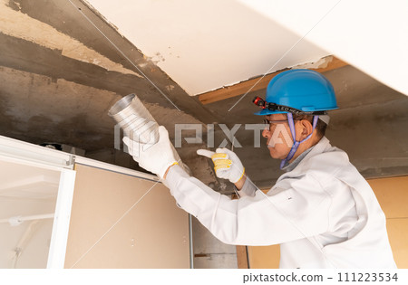 Renovation work: worker installing and checking ventilation ducts 111223534