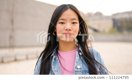 Asian young woman looking at camera outdoors Asian young woman looking at camera outdoors 111224795
