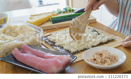 A woman making sushi rolls and seaweed rolls 111226573