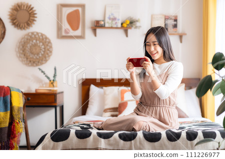 College woman looking at smartphone in her room 111226977