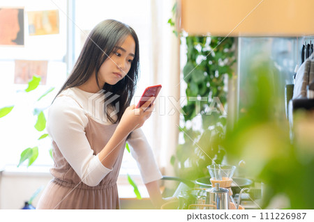 College woman looking at smartphone in her room 111226987