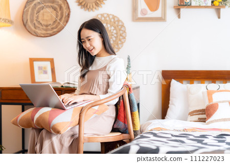 College woman looking at computer in her room College woman looking at computer in her room 111227023