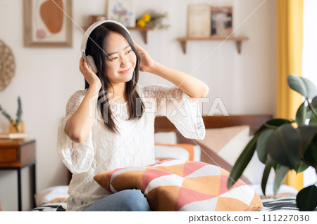 College woman listening to music with headphones College woman listening to music with headphones 111227030