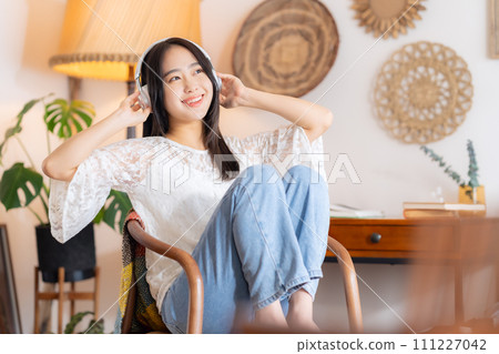 College woman listening to music with headphones College woman listening to music with headphones 111227042