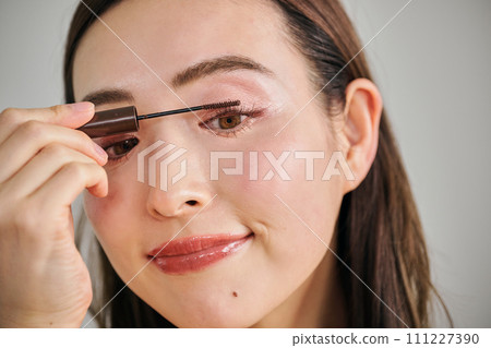 A woman in her 30s with long hair applying mascara A woman in her 30s with long hair applying mascara 111227390