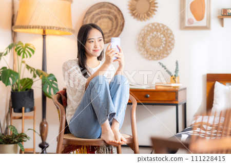College woman looking at smartphone in her room 111228415