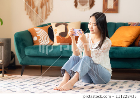 College woman looking at smartphone in her room 111228433
