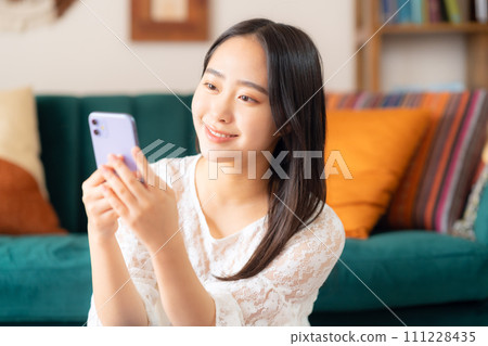 College woman looking at smartphone in her room 111228435