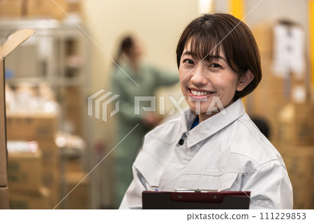 Female staff in work clothes working at a distribution warehouse Female staff in work clothes working at a distribution warehouse 111229853