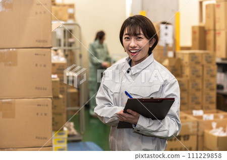 穿著工作服在配送倉庫工作的女員工 穿著工作服在配送倉庫工作的女員工 111229858