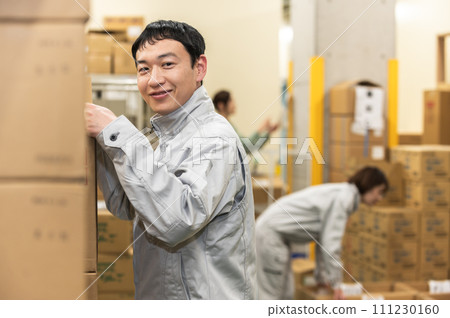A man in work clothes doing inspection work at a distribution warehouse A man in work clothes doing inspection work at a distribution warehouse 111230160