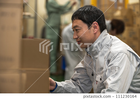 A man in work clothes doing inspection work at a distribution warehouse A man in work clothes doing inspection work at a distribution warehouse 111230164